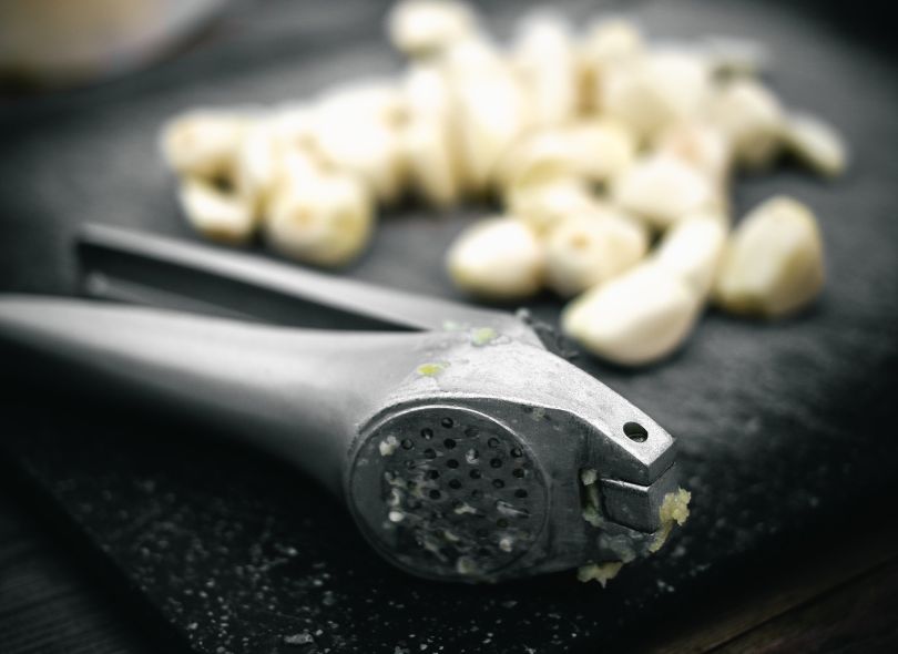 Garlic crusher with garlic.