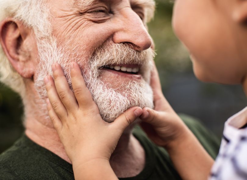 Grandchild playing with grandfathers face.