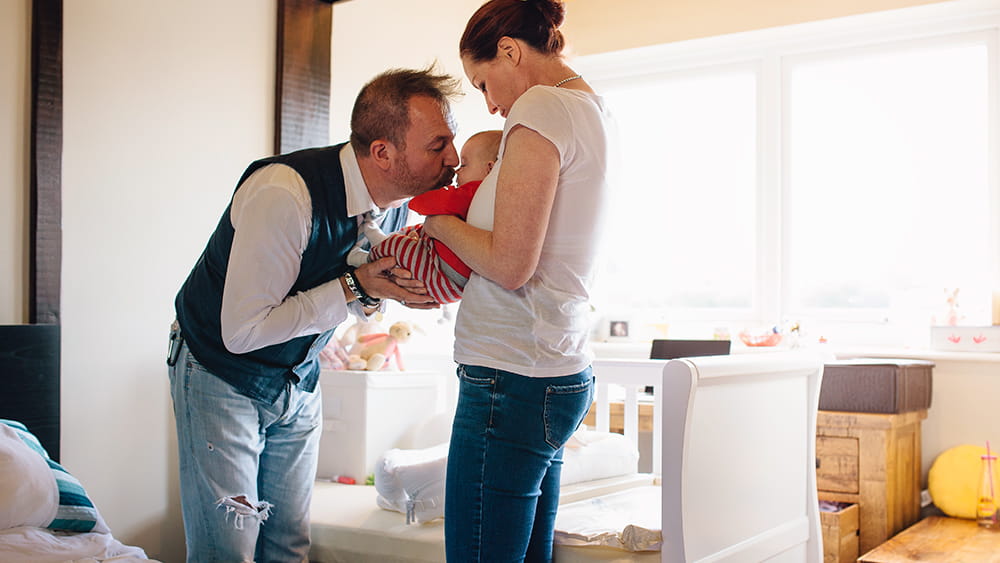 Father kissing baby held by mother