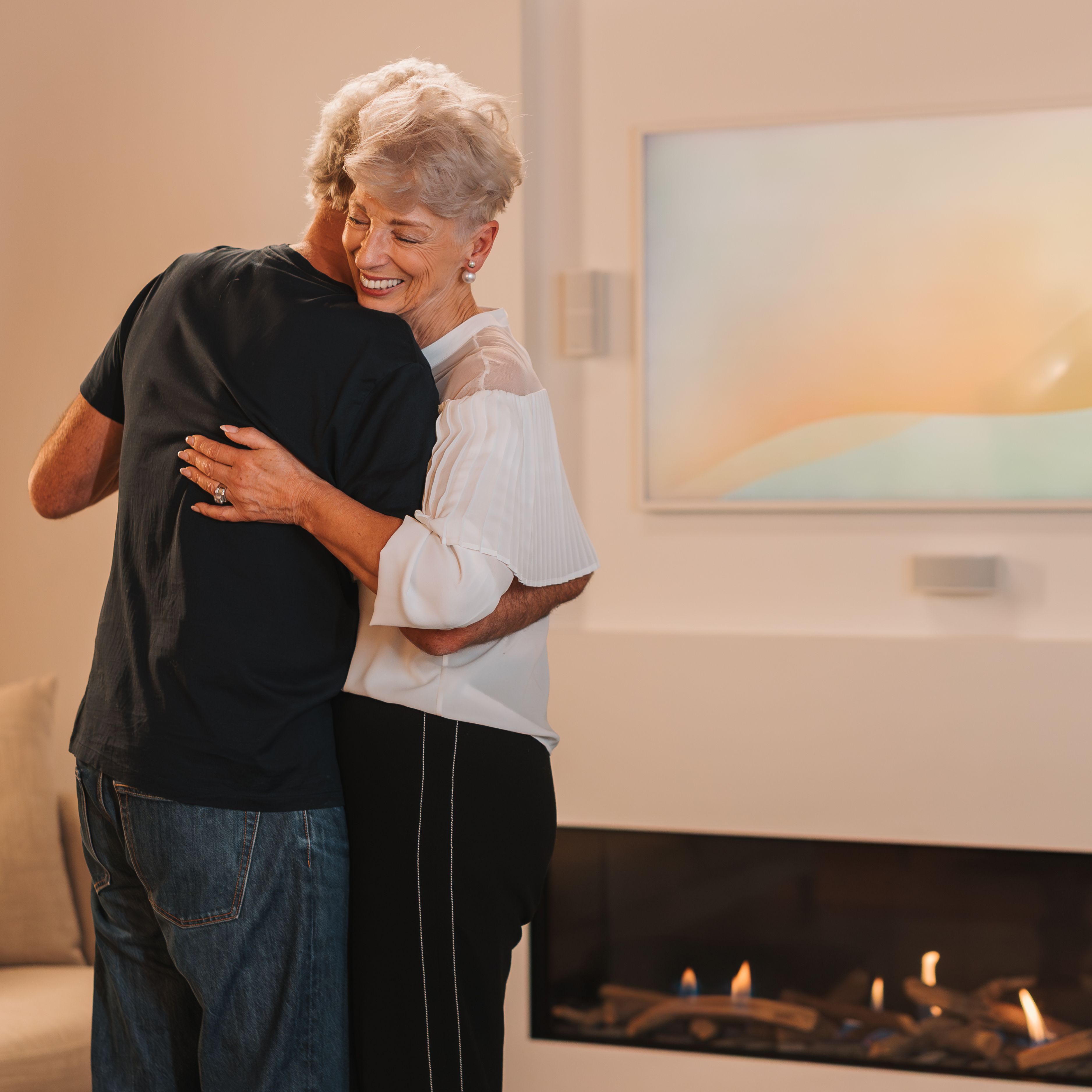 Couple dancing in their living room in front of natural gas fire.