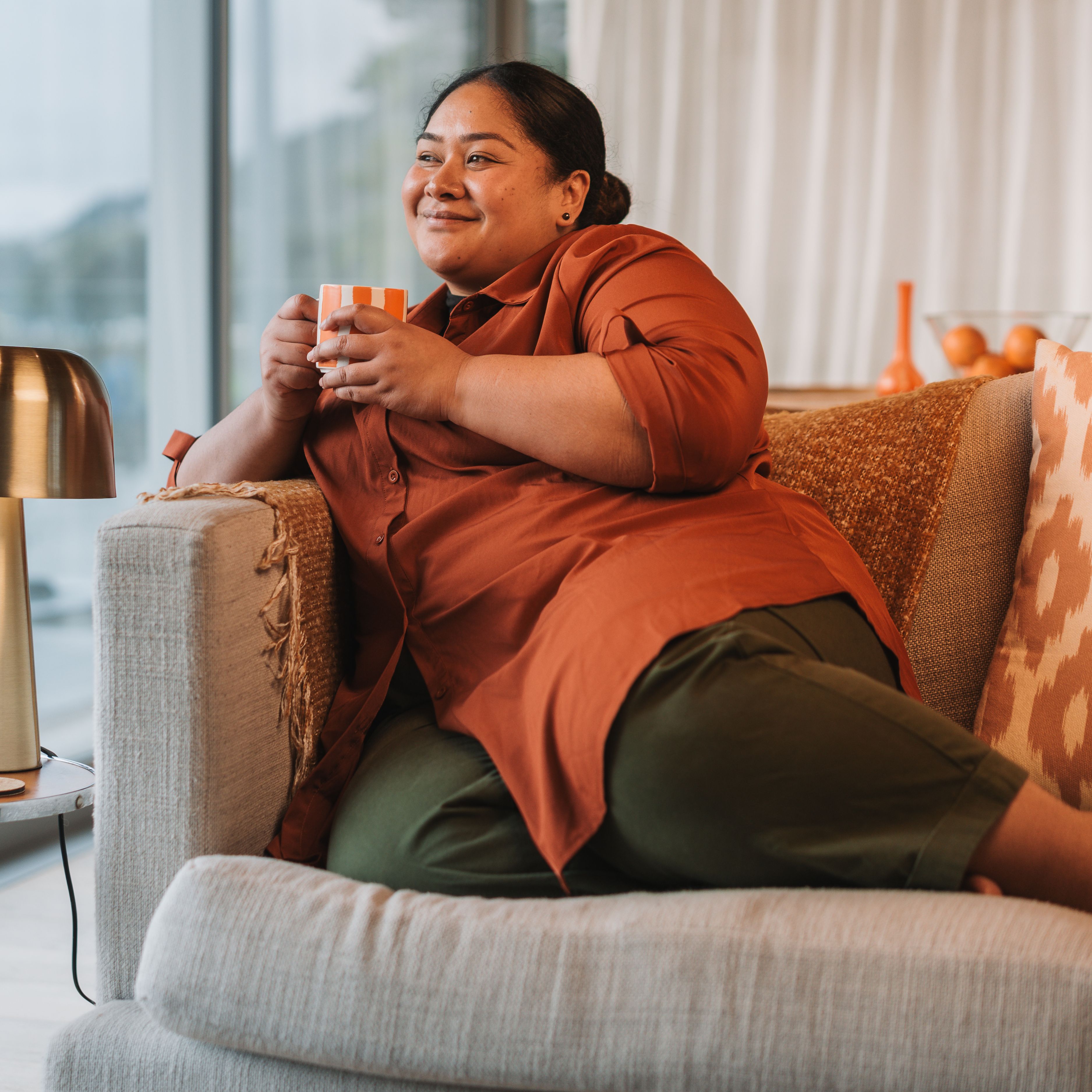 Woman relaxing on the couch with a cup of tea in a home heated by gas.
