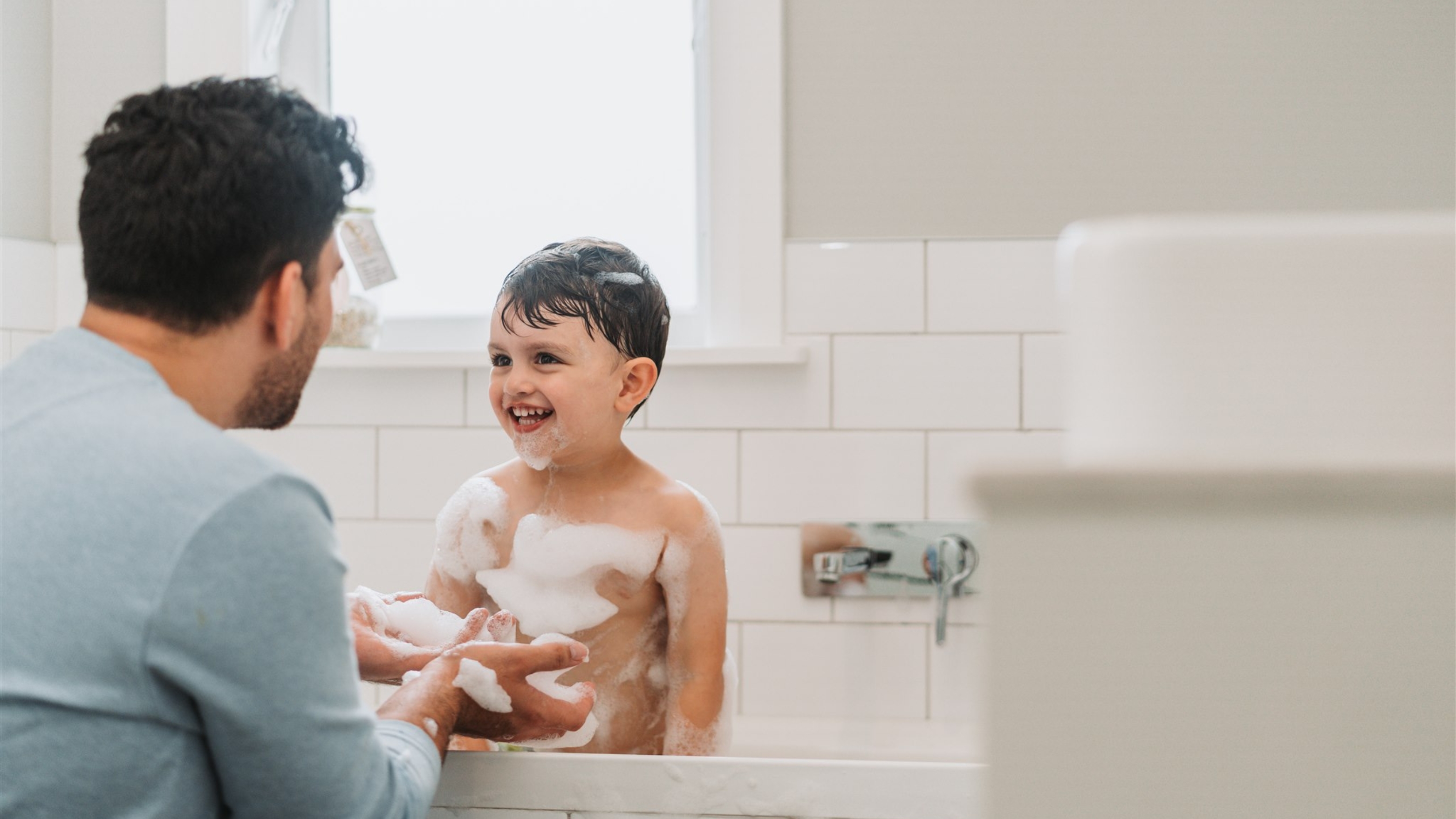 Boy enjoying bathtime with his Dad.
